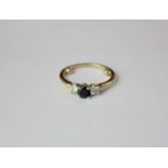 A three stone ring with central sapphire flanked by two white stones in 18ct yellow gold