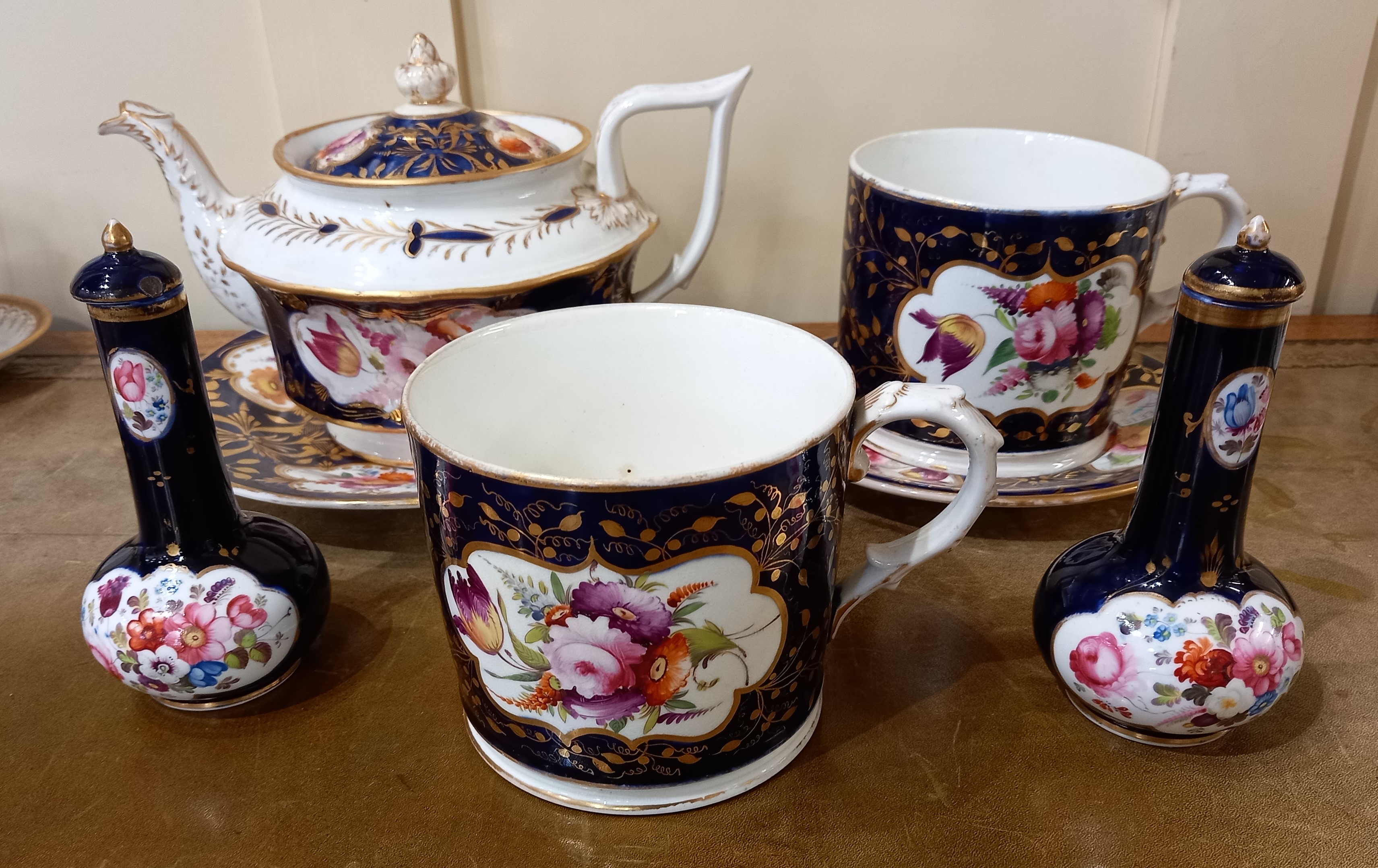 A collection of 19th century English porcelain painted with panels of flowers on a blue and gilt