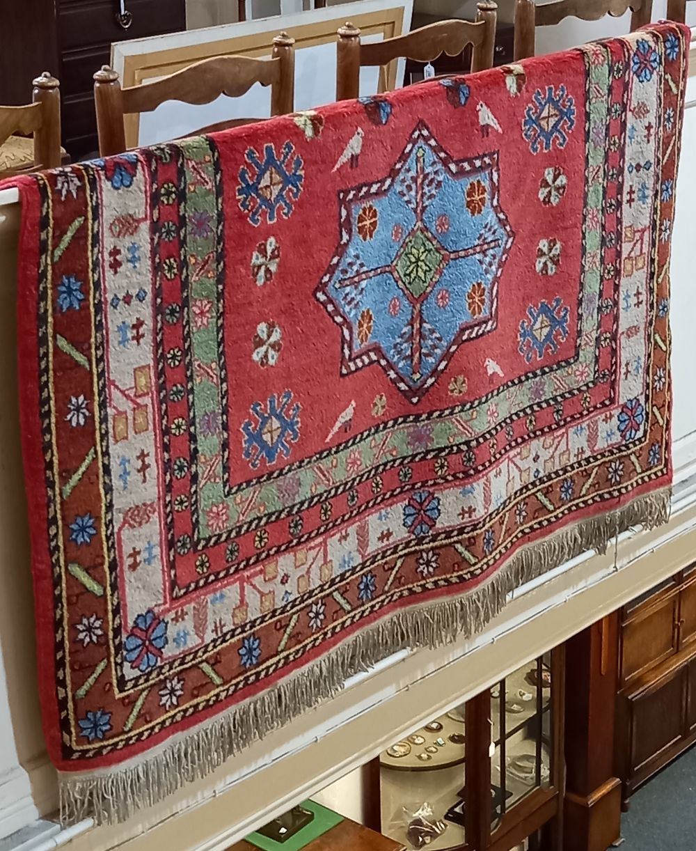 An Eastern rug, red ground, the field decorated with three large blue stars amongst birds and