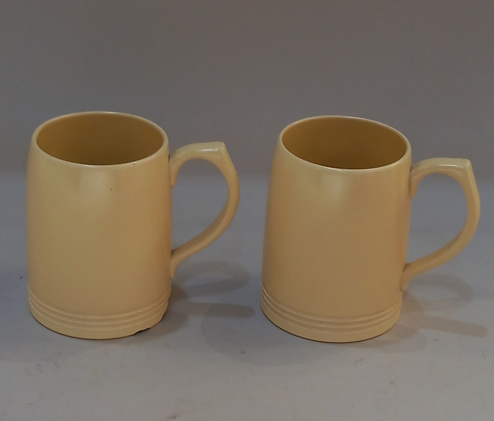 A pair of Keith Murray for Wedgwood yellow glazed pottery mugs printed and impressed marks to