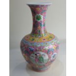 A Chinese pink ground famille rose porcelain vase, baluster shaped with fluted neck, decorated