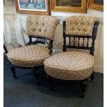 A pair of Victorian low chairs with button upholstered backs and ebonised frame on turned legs and
