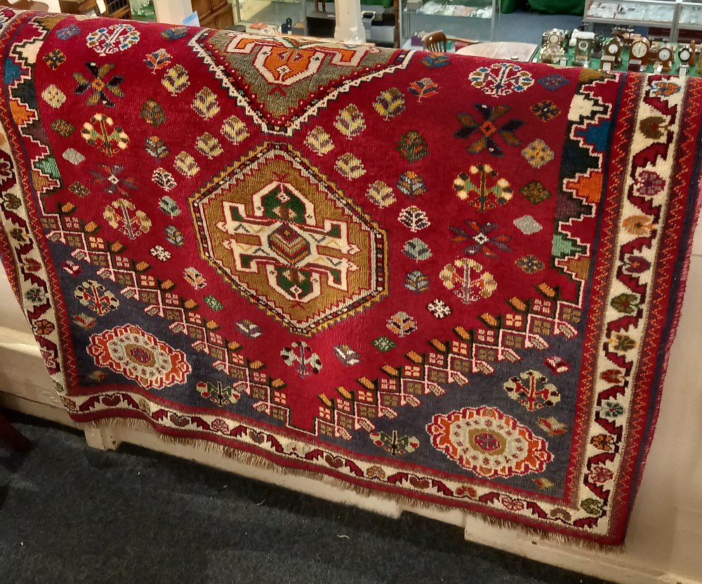 A Fired Earth hand woven rug, red ground, with three central medallions within a multiguard