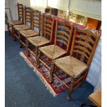 A set of six oak ladderback dining chairs with rush seats (one with replaced front stretcher)