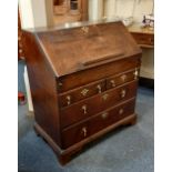 A George III oak bureau with fall front enclosing fitted interior of small drawers, pigeon holes and