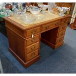 An oak pedestal desk with leather inset rectangular top above an arrangement of nine drawers with