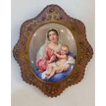 A 19th century Continental painted oval plaque of the Madonna and child, in a metal mounted wooden