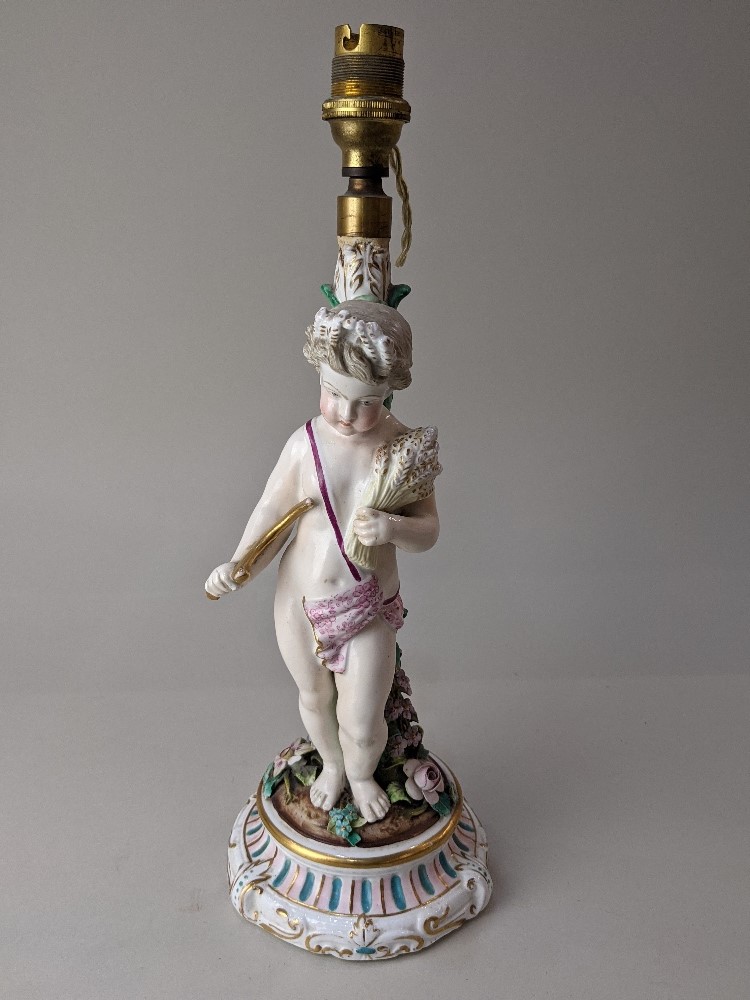 A 19th century porcelain candlestick converted to a table lamp, depicting a cherub representing