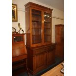A Victorian style bookcase, possibly a marriage, with two glazed panel doors enclosing four shelves,