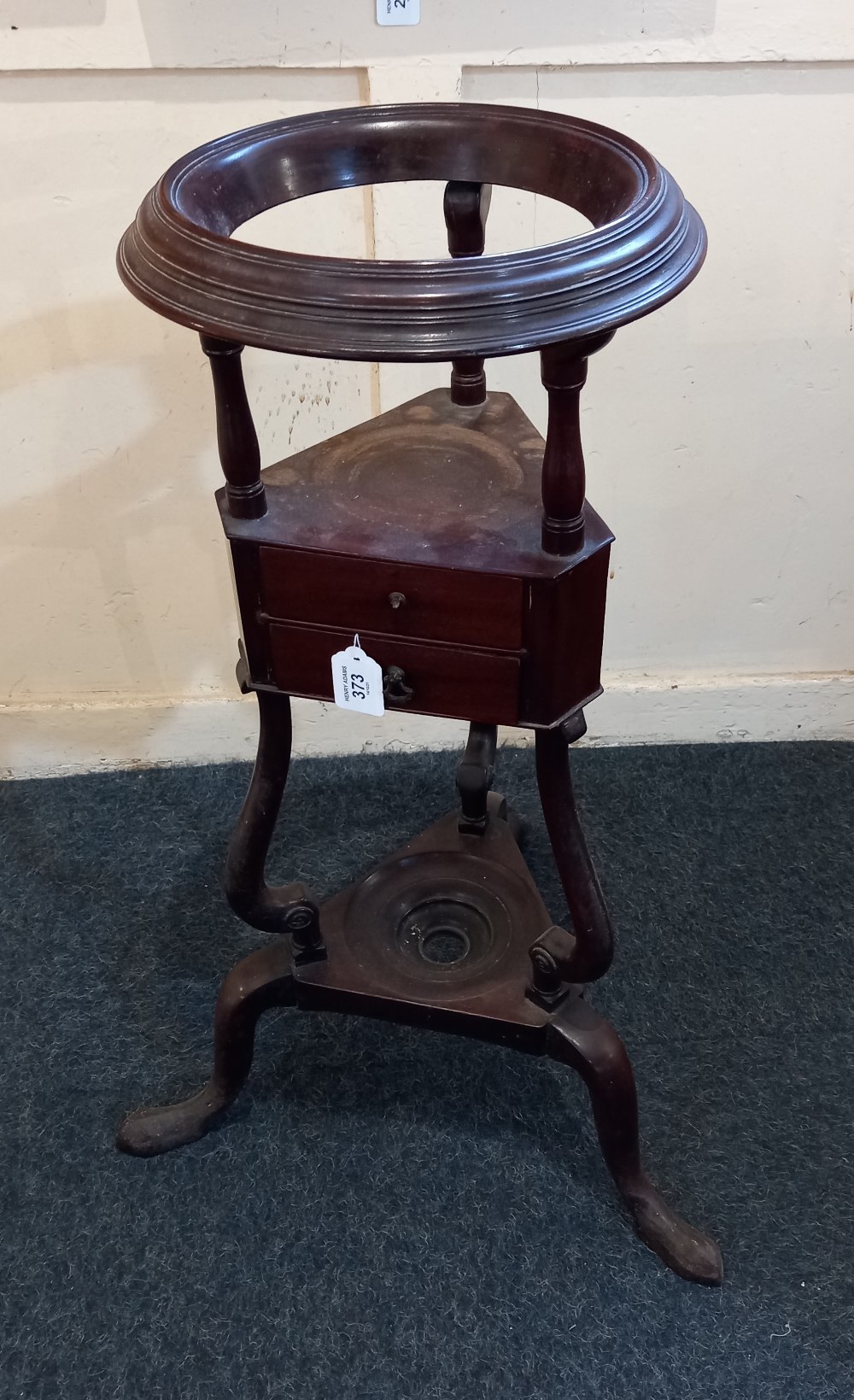 A George III mahogany circular washstand with ring top washbowl support, two triangular shaped