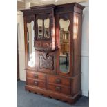 An Art Nouveau carved mahogany breakfront wardrobe central protruding cupboard with shaped