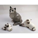 Three Beswick models of cats, comprising a grey Persian cat with green eyes, a Siamese cat, and a