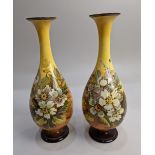 A pair of Doulton Lambeth Faience baluster vases with slender fluted necks, decorated with flowering
