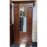 An Arts and Crafts oak hall wardrobe single mirrored door with copper strap hinges and fruit panels,