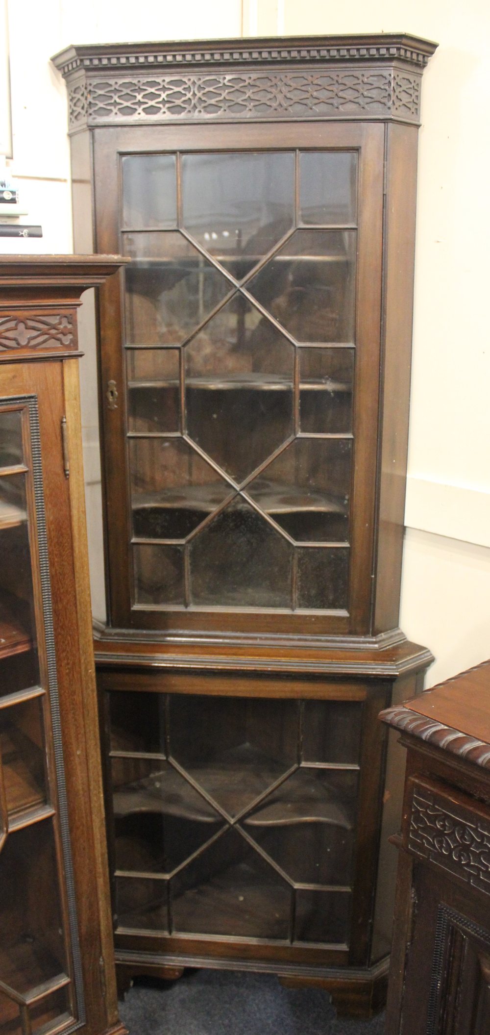 A mahogany glazed corner cabinet with dentil carved and blind fret cornice, top and base with glazed