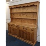 A pine dresser two shelf top with shaped cornice above four drawers and panelled cupboards on plinth