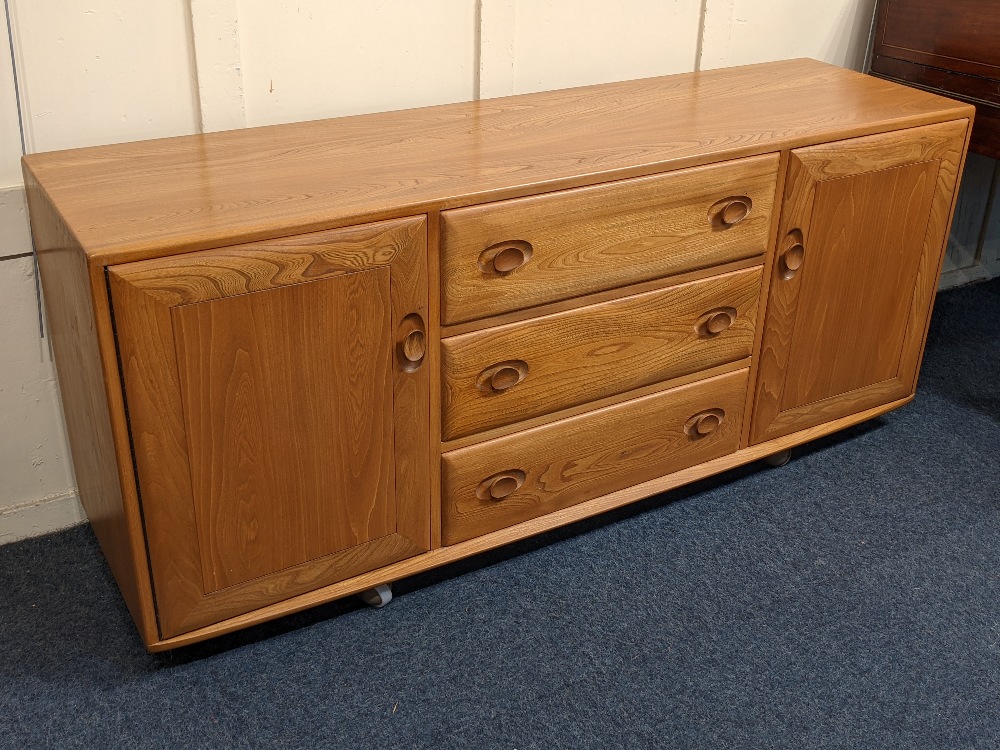 An Ercol light elm sideboard three central drawers with sliding cutlery tray between two cupboards