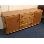 An Ercol light elm sideboard three central drawers with sliding cutlery tray between two cupboards