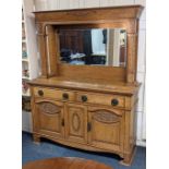 An Arts and Crafts carved oak sideboard with mirror back and column supports two drawers with drop