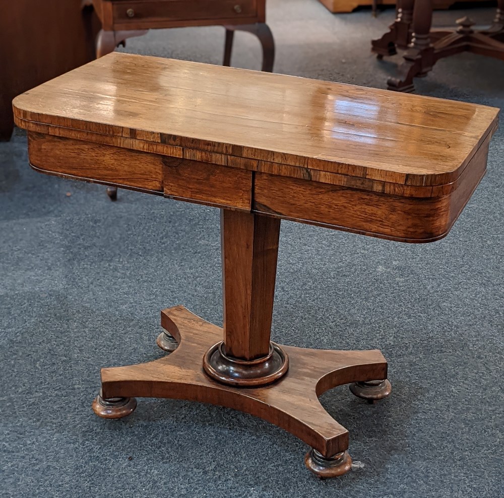 A Victorian rosewood card table with baise lined fold over rectangular top on facetted stem and