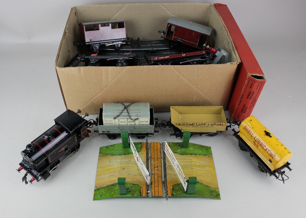 A Hornby O gauge clockwork model railway locomotive and seven rolling stock, together with a level