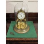 A brass anniversary clock, under a glass dome, on metal base, with key (a/f)