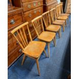 A set of six Ercol light elm dining chairs with spindle backs and solid seats and sloping legs