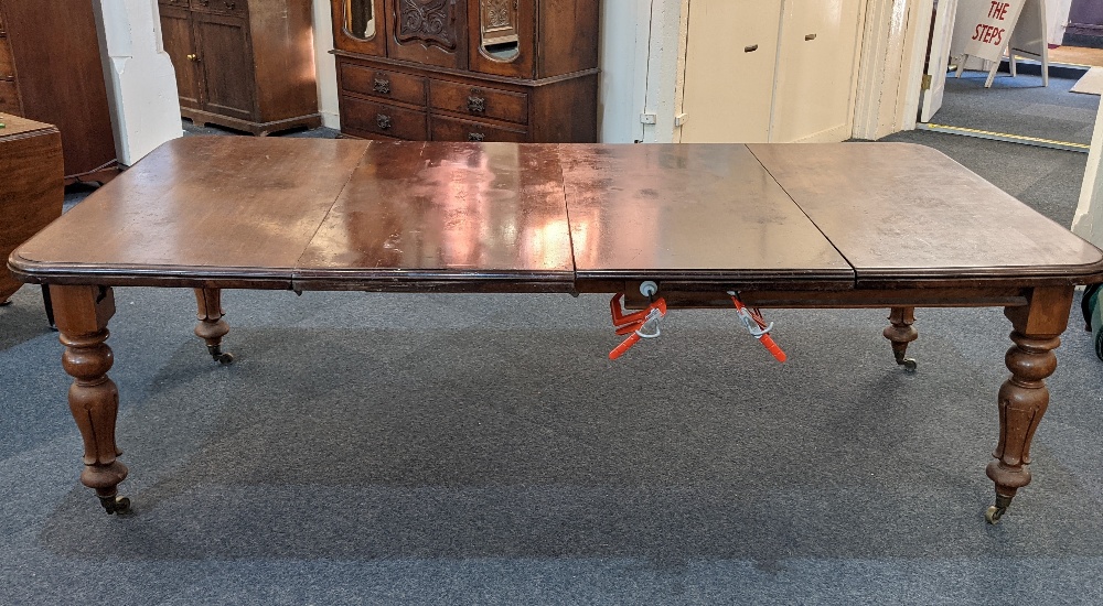 A Victorian mahogany extending dining table, with two extra leaves, the rectangular moulded top with