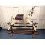 A dapple grey and cream painted rocking horse with white horsehair mane and tail, leather saddle, on