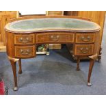 A kidney shaped writing desk with green leather top, five drawers with brass drop handles, on