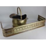 A brass helmet shaped coal scuttle and a pierced brass fire fender, 94cm