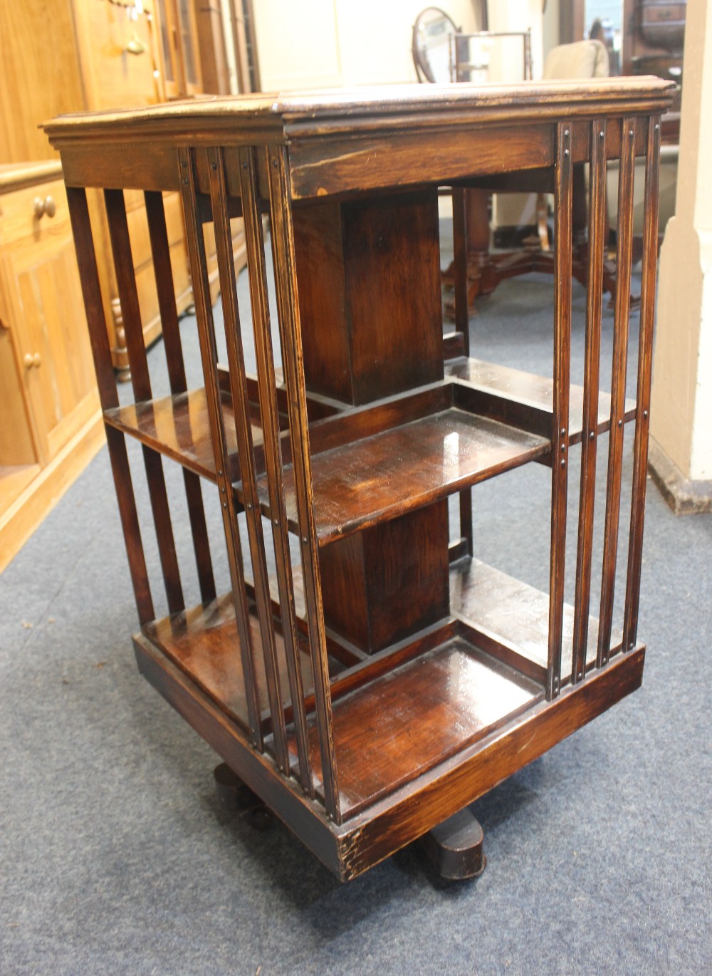 An early 20th century walnut two tier revolving bookstand on swivel base with castors, 47cm