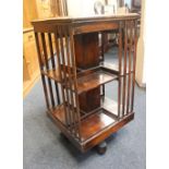 An early 20th century walnut two tier revolving bookstand on swivel base with castors, 47cm