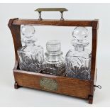 A brass mounted oak tantalus, with key, 32cm, containing a pair of cut glass decanters, and a
