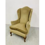 A GREEN VELOUR UPHOLSTERED WINGED EASY CHAIR