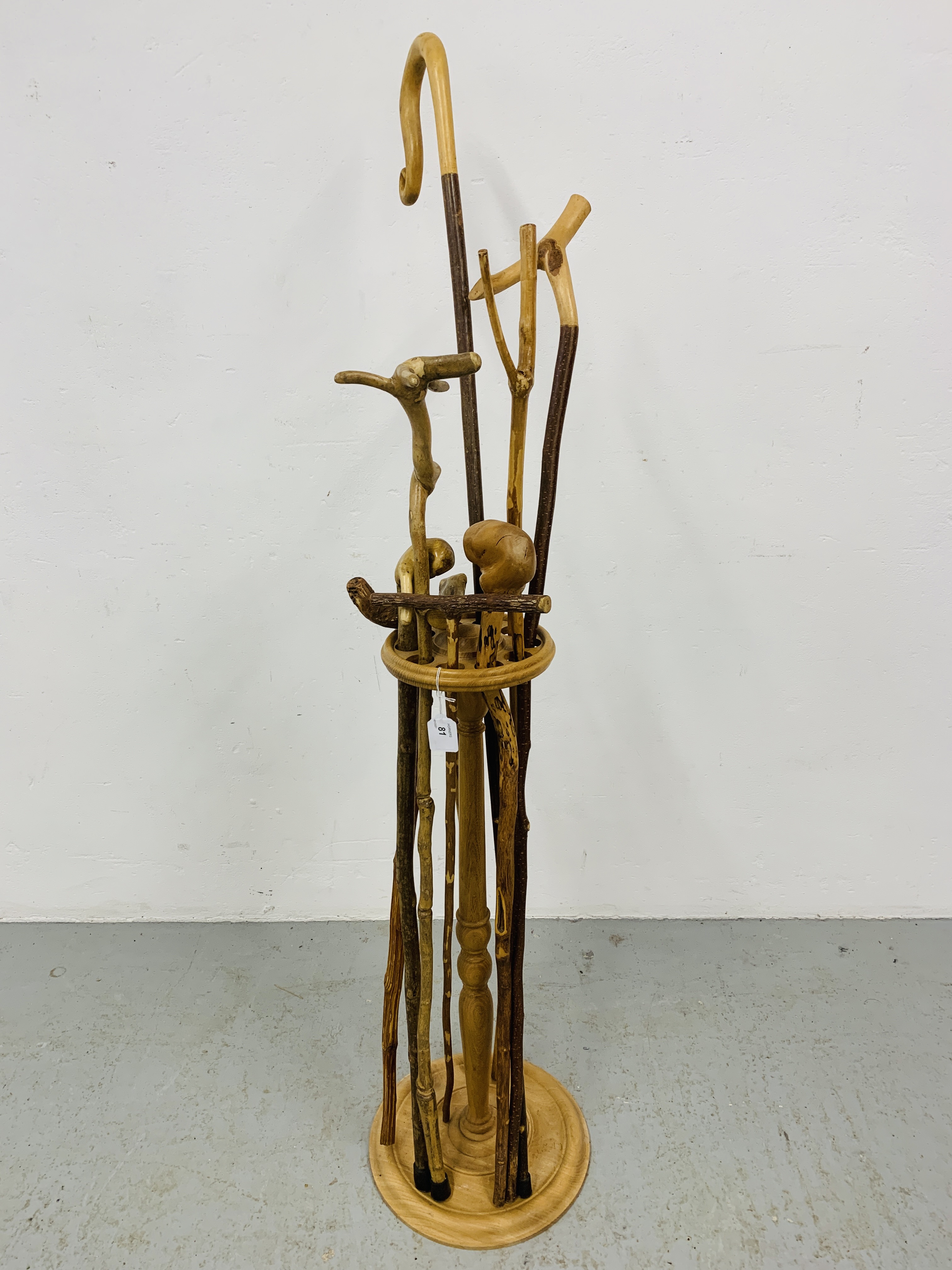 A HAND TURNED STAND CONTAINING A COLLECTION OF WALKING STICKS