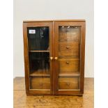 A MINATURE MAHOGANY COLLECTORS CABINET THE TWO GLAZED DOORS ENCLOSING A FITTED INTERIOR WIDTH 38cm,