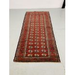 A BALUCHI RED AND BLUE PATTERNED CARPET 2.25 x 1.02. 1.