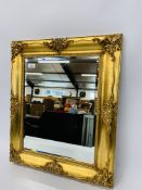 A REPRODUCTION CLASSICAL GILT FRAMED WALL MIRROR WITH BEVELLED GLASS.