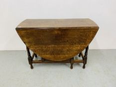 AN OAK GATELEG DINING TABLE WITH TURNED SUPPORTS - THE OVAL TOP EXTENDED L 106CM. W 141CM.