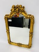 A REPRODUCTION GILT FRAMED WALL MIRROR THE FRAME DECORATED WITH CHERUBS