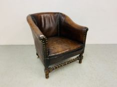 AN ANTIQUE TAN LEATHER UPHOLSTERED TUB CHAIR WITH STUDDED DETAIL AND BARLEY TWIST FRONT STRETCHER