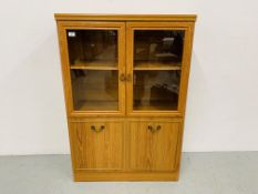 A MODERN WOODGRAIN FINISH GLAZED CABINET WITH CUPBOARD BASE - W. 81CM. H 120CM. D 34CM.