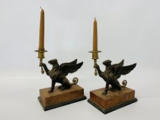 A pair of bronze Griffin candlesticks on simulated marble bases.