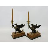 A pair of bronze Griffin candlesticks on simulated marble bases.