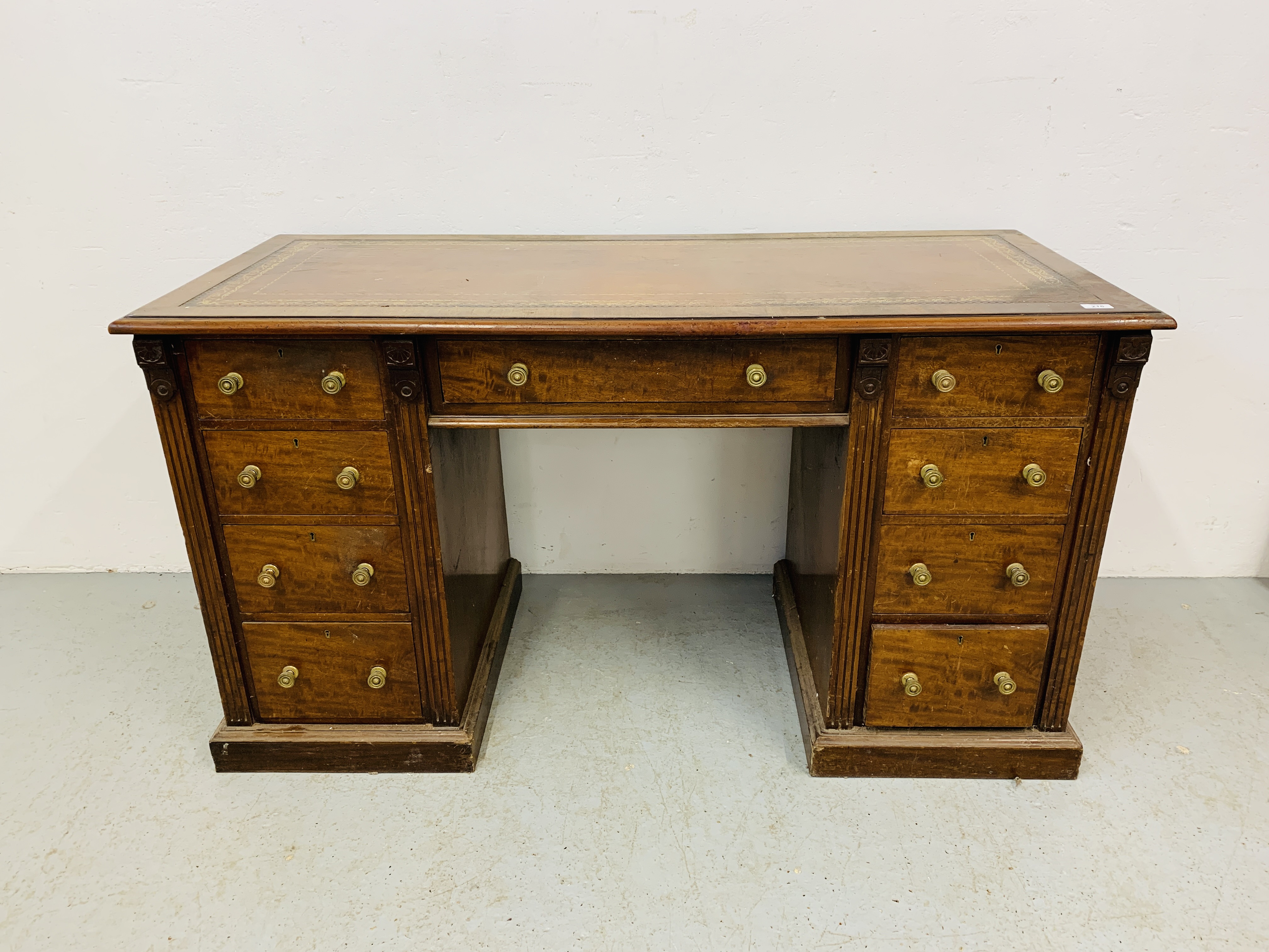 An Edwardian mahogany single piece nine drawer pedestal desk with inlaid tan leather top,