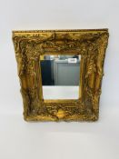 A HEAVILY GILT DECORATED WALL MIRROR 45CM X 40CM.