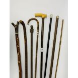 A group of eight various walking sticks including one calibrated in inches and two having silver
