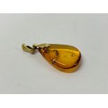 AN AMBER PENDANT ON A YELLOW METAL SUSPENSION LOOP.