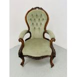 A VICTORIAN MAHOGANY SPOON BACK OPEN ARMCHAIR WITH BUTTON BACK AND GREEN VELOUR UPHOLSTERY